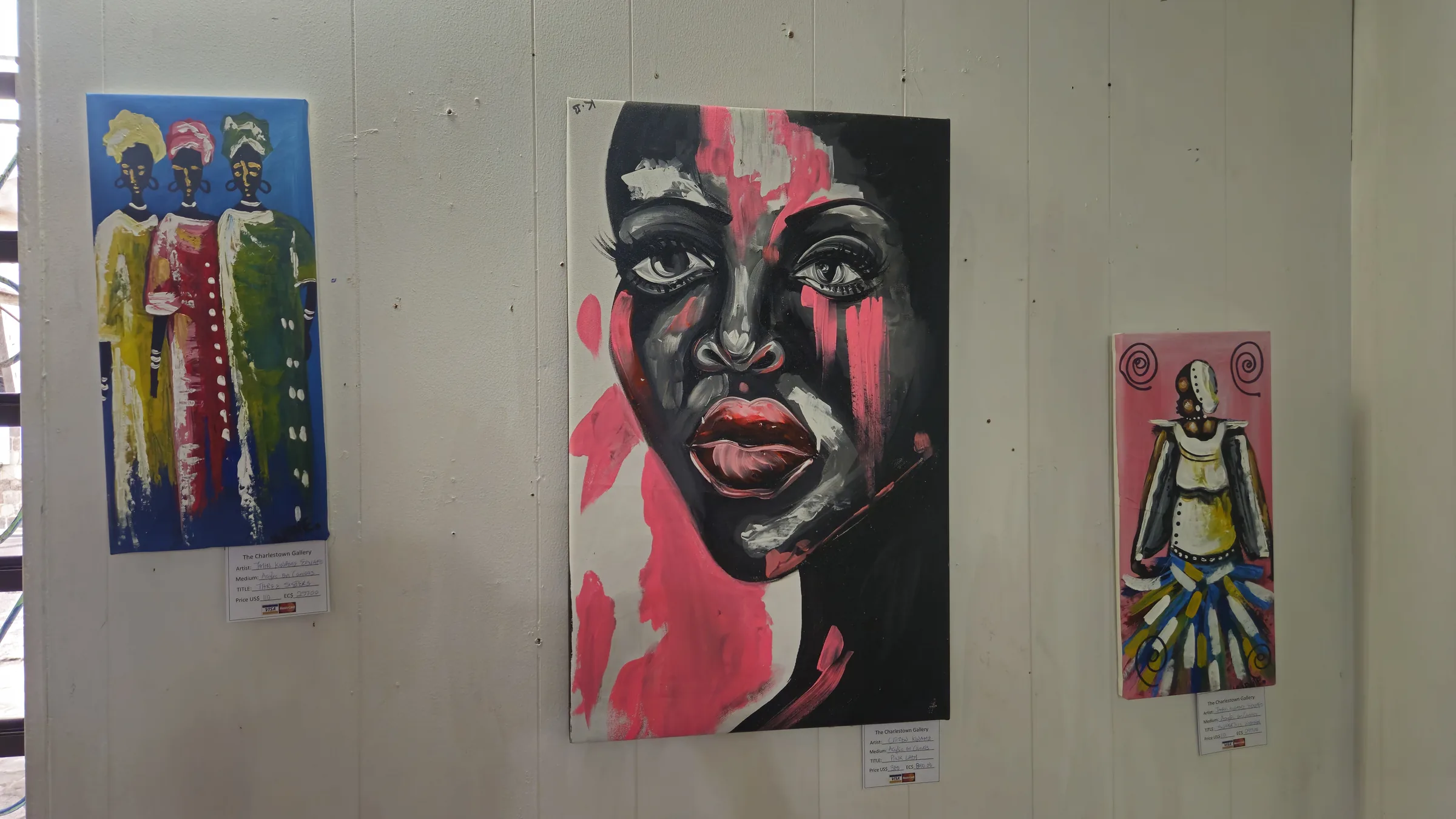 A visitor looking closely at paintings on display at Charlestown Gallery